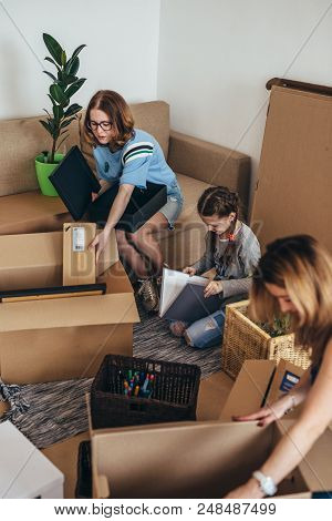 Family Unpacking Cardboard Boxes At New Home.