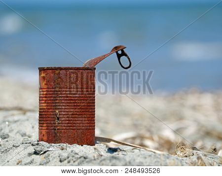 Rusty Tin Can On The Beach With Blue Sea.