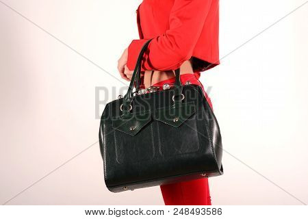 Slender Girl In A Red Jacket And Jeans With A Green Bag Stands Sideways