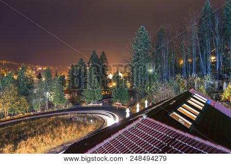Night View Of Predeal, A City In The Mountains. Light Trails Over Winding Road