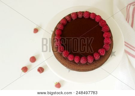 Chocolate Brownie Cake With Raspberries And Chocolate Icing On A Light Background. Selective Focus.
