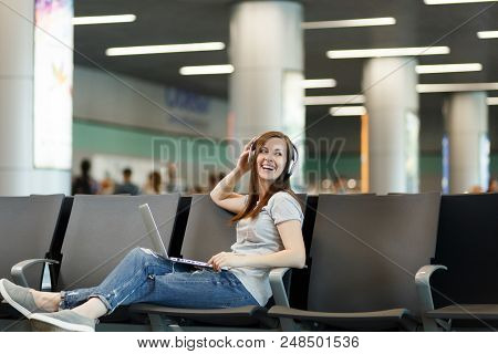 Young Laughing Traveler Tourist Woman With Headphones Listening Music Working On Laptop, Wait In Lob
