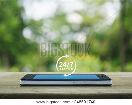 24 Hours Service Icon On Modern Smart Phone Screen On Wooden Table Over Blur Green Tree In Park, Ful