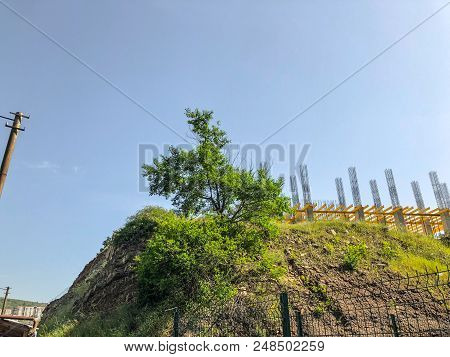 A Beautiful View Of The Hillock With  Green Grass Against The Sky, Construction Of A New Building, A