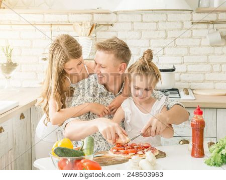 dad with two little daughters preparing pizza in the kitchen