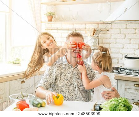 dad with two little daughters have a fun in the kitchen