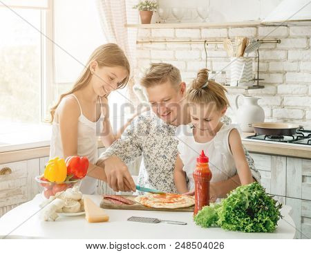 dad with two little daughters preparing pizza in the kitchen