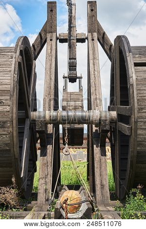 Fragment Of An Ancient Wooden Catapult Against The Background Of Fortress Walls