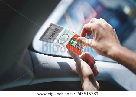 Switzerland, June, 2018: Man Glueing The Swiss Highway Sign On Front Glass Of His Car.