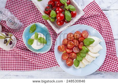 Traditional Italian Salad With Fresh Cherry Tomatoes And Soft Mazarella Cheese, With Basil And Olive