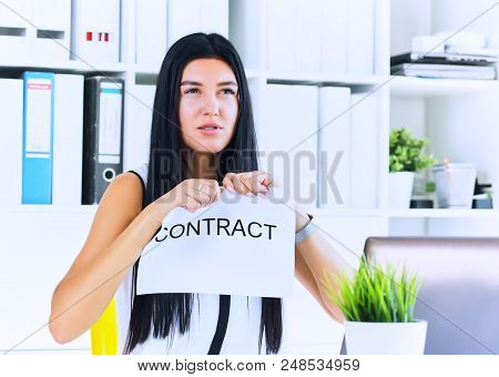 Young Angry Female Office Worker Ripping Contract At The Desk.