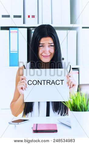 Young Unhappy Female Office Worker Ripping Contract At The Desk.