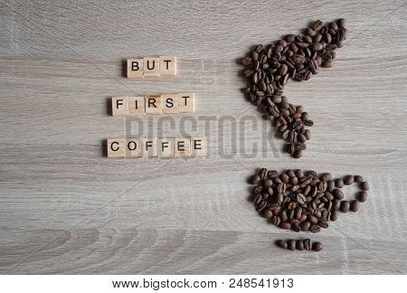 Roasted Coffee Beans Placed In The Shape Of A Cup And Saucer On Wooden Background, With But First Co