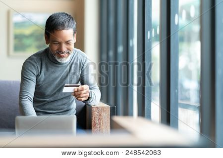 Happy Mature Man Holding Credit Card Paying Online By Using Laptop For Payment. Asian Senior Male Sm