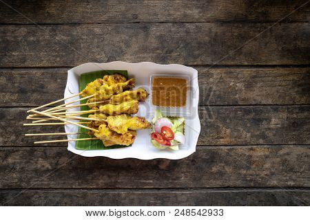 Top View Delicious Pork Satay Skewers With Peanut Dipping Suace And Sider In White Paper Box On Wood