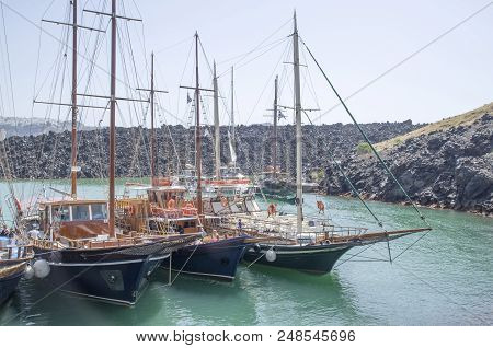 Many Wooden Ships On Port Of Nea Kameni Volcanic Island Near Santorini