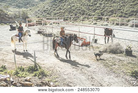 Couple Riding Horses Starting From Ranch With Their Dogs Following Them - Happy People Having Fun On