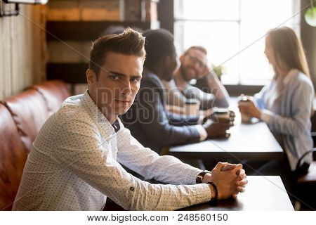 Sad Millennial Man Not Looking At Multiracial Friends Smiling And Having Fun Drinking Coffee In Cafe