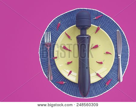 A Large Vibro Massager Is In A Green Round Dish. A Few Small Hot Chili Peppers Are Scattered Around.