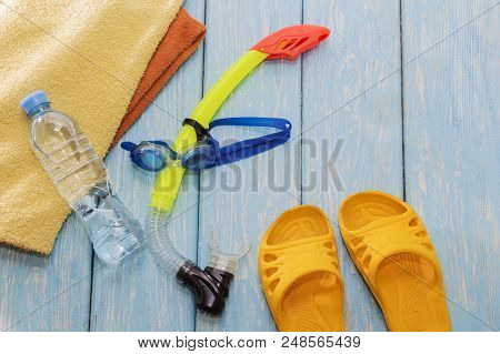 Glasses Diving Mask And Snorkel, Clear Water Bottle, Bright Slates On Wooden Blue Background
