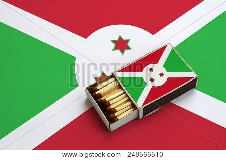 Burundi Flag  Is Shown In An Open Matchbox, Which Is Filled With Matches And Lies On A Large Flag.