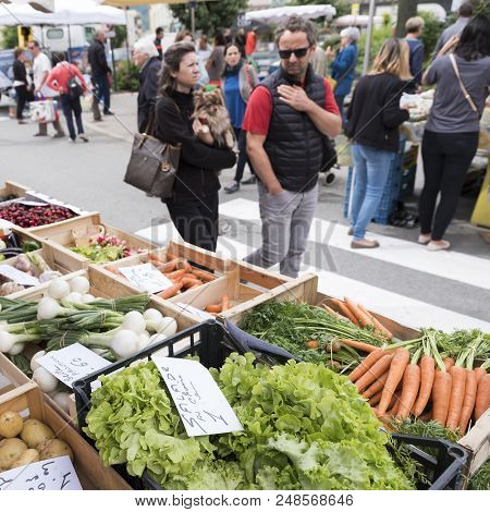 Briancon, France, 10 June 2018: Man And Woman Look At Vegetables On Open Air Market Of Briancon In T