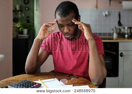Indoor Shot Of Young African American Man Pressing Fingers To Temples Feeling Pain In His Head Tryin