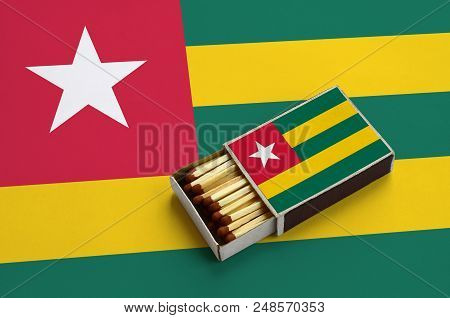 Togo Flag  Is Shown In An Open Matchbox, Which Is Filled With Matches And Lies On A Large Flag.