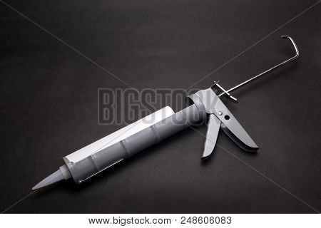 Gray Caulk Gun With Container On A Black Background
