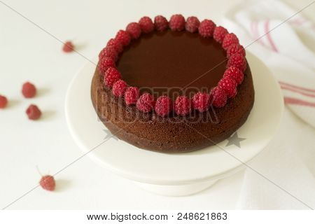 Chocolate Brownie Cake With Raspberries And Chocolate Icing On A Light Background. Selective Focus.