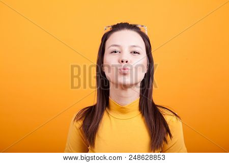 Pretty Girl Making Kiss To The Camera On Yellow Background