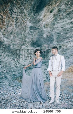 Beautiful Couple Near The Rocks, Looking With A Smile At Each Other