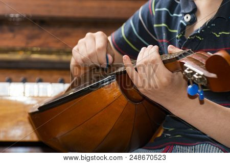 The Boy Plays The Guitar And Takes Chords, Dombra On The Background Of The Piano.