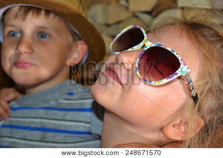 Toned Picture Of A Girl In Sunglasses, Hugs Her Younger Brother.