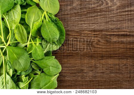 Fresh Baby Spinach Leaves Top View On Brown Wood Background Left Corner