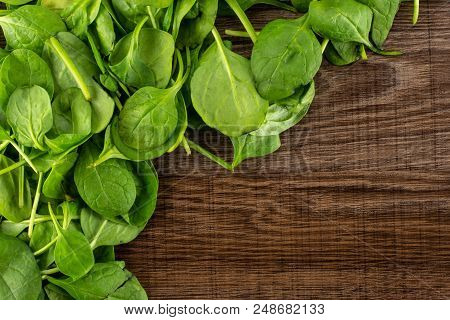 Fresh Baby Spinach Leaves Top View On Brown Wood Background Left Upper Corner