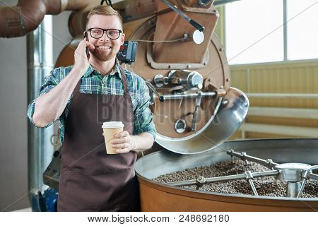 Waist Up Portrait Of Handsome Modern Barista Wearing Apron Speaking By Phone While Standing At Coffe