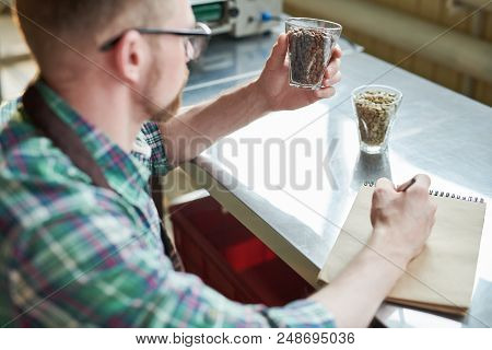 Over The Shoulder View Of Modern Barista Holding Coffee Beans And Making Notes While Checking Qualit
