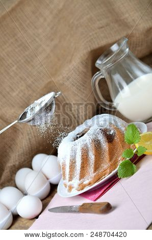 Woman Sprinkles A Homemade Marble Cake With Sugar, Milk, Eggs, Melissa Leaves, And Butter, Still Lif