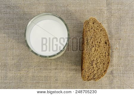 Slice Of Rustic Bread And A Glass Of Milk On A Linen Tablecloth, Top View