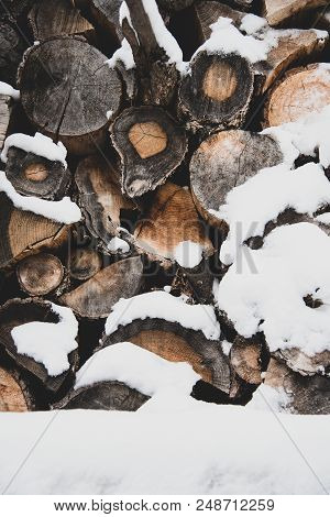 Heap Of Oak Firewood Covered With Snow, Preparation For The Winter Season, Background With Matte Ton