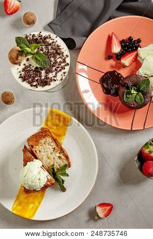 Dessert Mix of Truffle Panna Cotta, Chocolate Fondant and Apple Charlotte with Ice Cream. Sweet Collection with Blancmange, Apple Cake, Brownie and Strawberries on Grey Background Top View