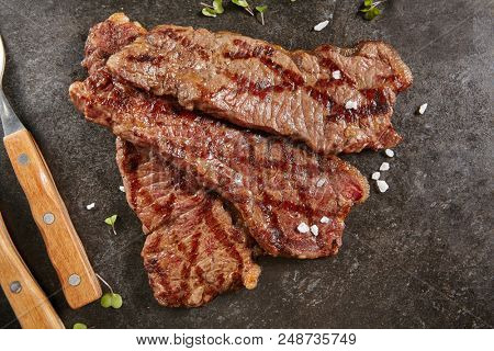 Hot Grilled Whole Gaucho Steak on Black Stone Background. Fresh Juicy Medium Rare Beef Grillsteak. Barbecue Meat Top View Close Up