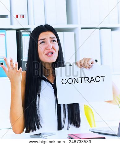 Young Angry Female Office Worker Ripping Contract At The Desk.
