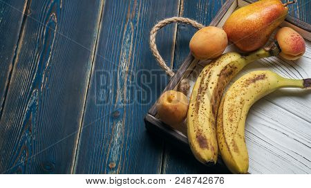Fresh Fruit On A White Wooden Tray: Banatas, Pears, Apricots. Countryside Setting. Top View. Copy Sp