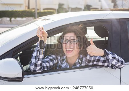 Young Woman In Car Shows Thumbs Up And Key.
