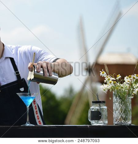 Bartender Workplace. Bartender On The Street Catering Bar Preparing A Coctail In A Martini Glass, Se