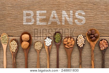Beans And Lentils In Wooden Spoon With White Painted On Wood Background. Groundnut, Walnuts, Macadam