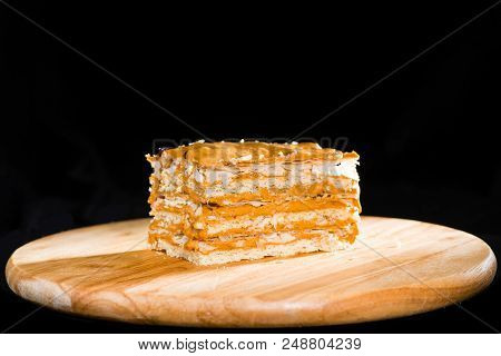 Close-up Delicious Cake Of Puff Pastry With Sour Cream On A Wooden Plate On Dark Background