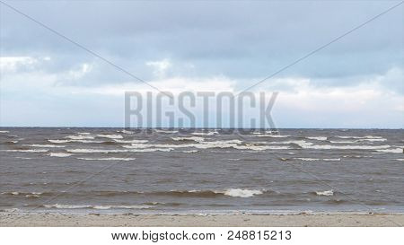 Sea Coastal Waves Rolling On Empty Sandy Beach, Stormy Cloudy Sunrise Skyview. Sea Waves On Sandy Be